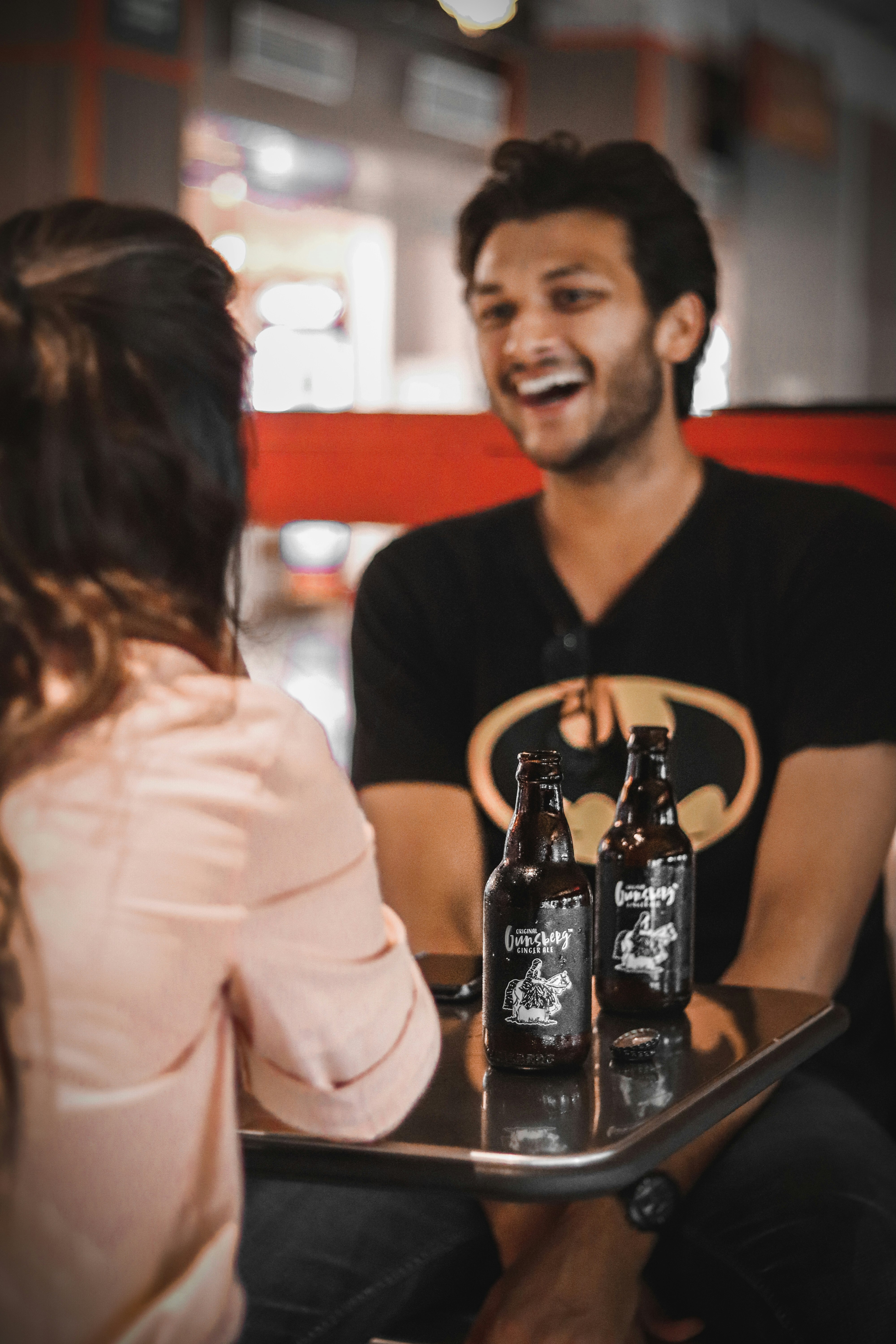 man in black Batman t-shirt sitting near table with bottles